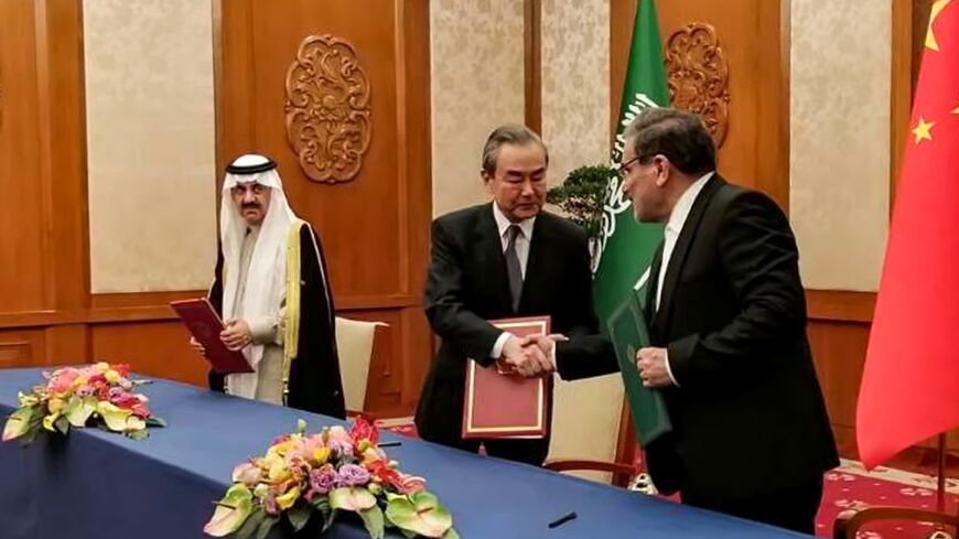 The Secretary of the Supreme National Security Council of Iran Ali Shamkhani (R) shaking hands with the Director of the Office of the Central Foreign Affairs Commission of the Chinese Communist Party Wang Yi (C) during a meeting with Saudi Arabia's National Security adviser and Minister of State Musaad bin Mohammed al-Aiban (L)