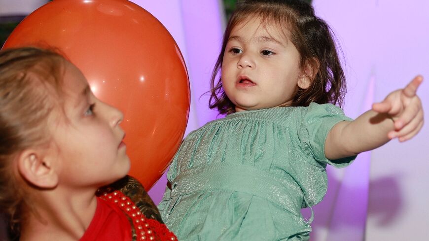 Afghan toddler Maryam, who was bundled onto an evacuation flight after her parents were killed in a huge bomb blast at Kabul airport in 2021, is reunited with her family and seen held by one of her sisters at an orphanage in Doha