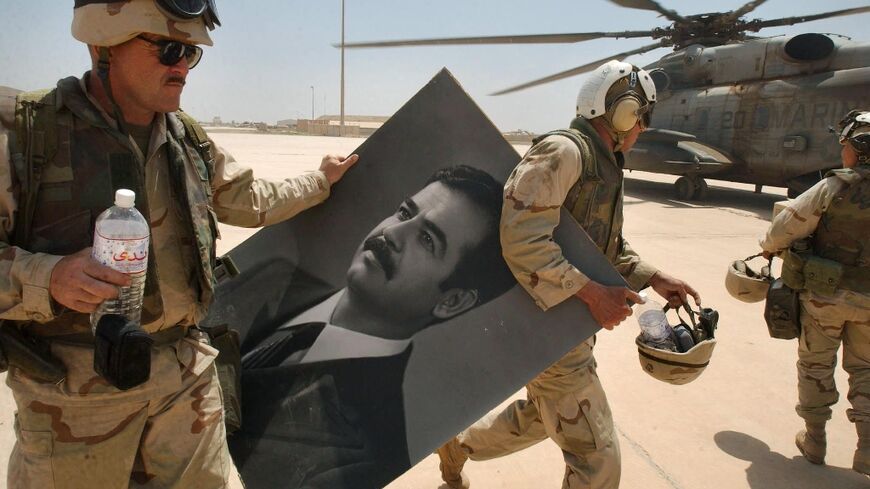US Marines carry a portrait of toppled Iraqi president Saddam Hussein at the international airport in Baghdad, in this file photo from April 14, 2003 