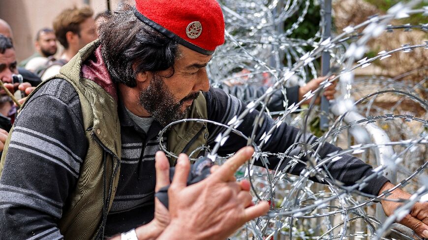 Protesters try to remove the barbed wire fence outside the government palace headquarters in the centre of Beirut