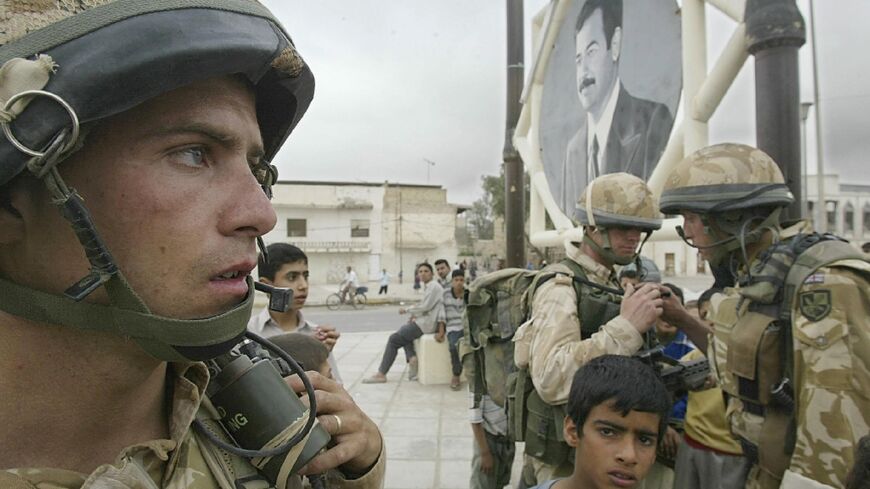 British troops seen next to a portrait of Iraqi president Saddam Hussein while they patrol Basra's old city, in a file photo from April 7, 2003 