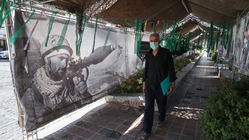 An Iranian man walks past banners at a street exhibition by Iran's army and paramilitary Revolutionary Guard force to celebrate "Defence Week", marking the 41th anniversary of the start of 1980-88 Iran-Iraq war, at the Baharestan Square in Tehran, on September 25, 2021. (Photo by Atta KENARE / AFP) (Photo by ATTA KENARE/AFP via Getty Images)