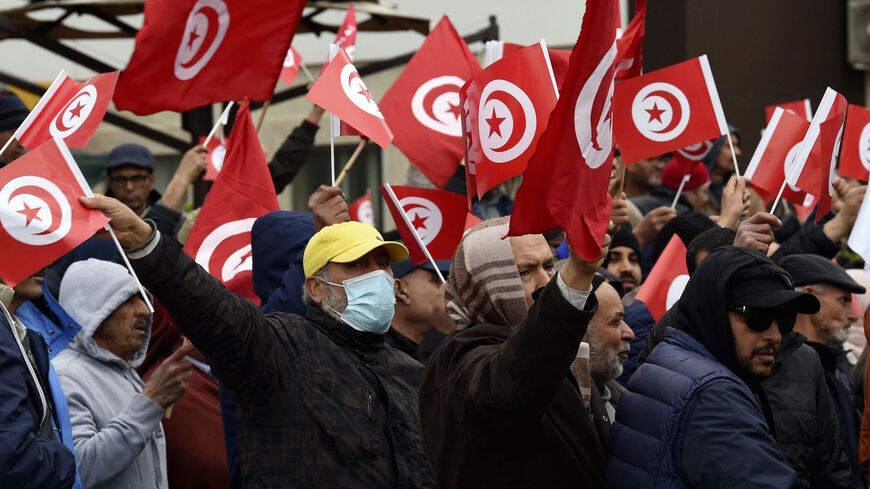 Tunisian protesters raise placards and national flags.