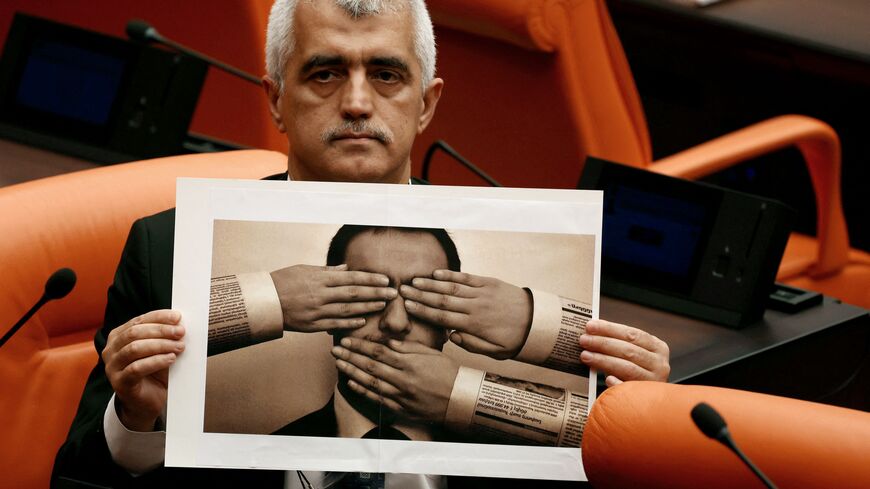 Peoples' Democratic Party (HDP) MP Omer Faruk Gergerlioglu holds a photograph depicting censorship while attending a session on a government-sponsored bill that criminalizes "disinformation" at the Turkish Grand National Assembly (TBMM) on October 13, 2022, in Ankara. (Photo by ADEM ALTAN/AFP via Getty Images)