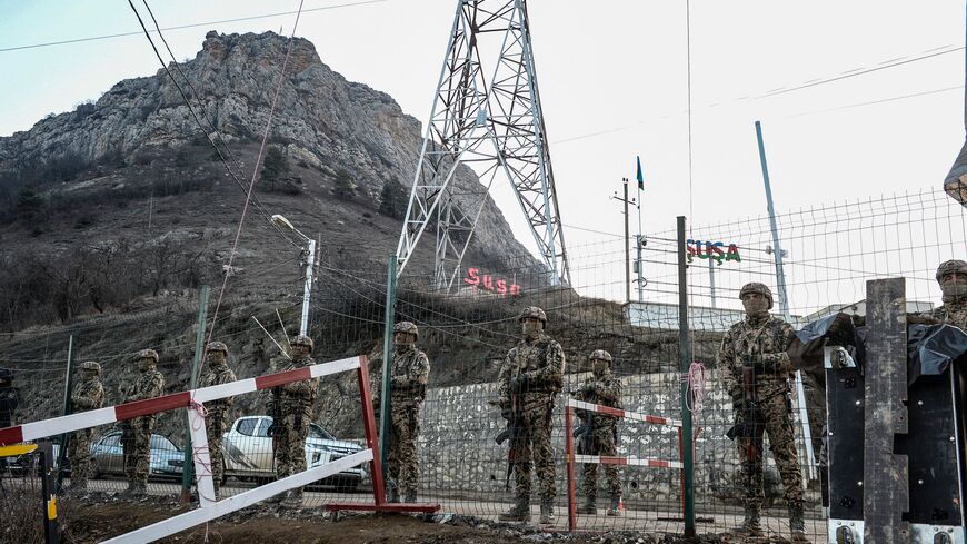 Azerbaijani servicemen stand guard at a checkpoint at the Lachin corridor, the Armenian-populated breakaway Nagorno-Karabakh region's only land link with Armenia, as Azerbaijani environmental activists protest what they claim is illegal mining, on December 26, 2022. 