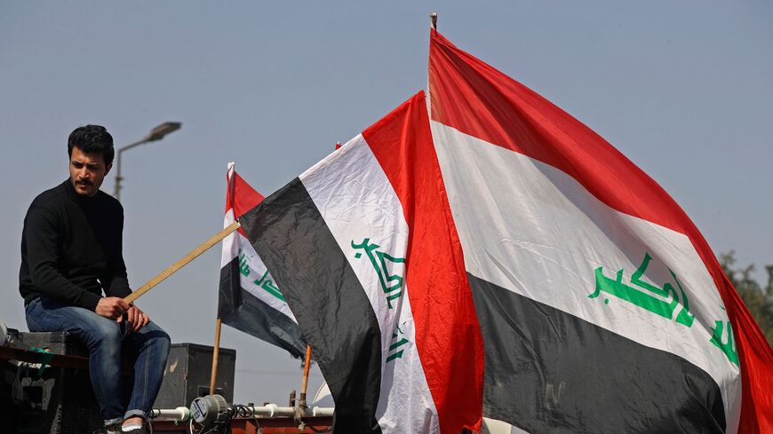 Demonstrators lift national flags during a protest near Baghdad's Green Zone on February 27, 2023.