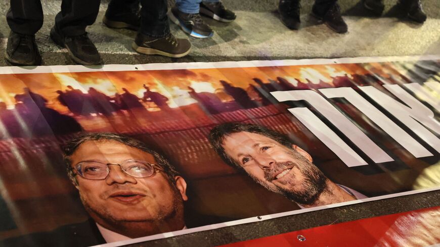 Israelis stand next to a poster with the portraits of Minister of National Security Itamar Ben-Gvir and Finance Minister Bezalel Smotrich.