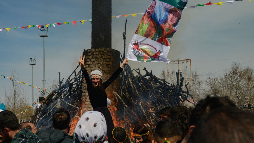 A reveller flashes the V-sign in front of a bonfire during a gathering of Turkish Kurds for Newroz (or Nowruz) celebrations marking the Persian New Year in Diyarbakir, southeastern Turkey, on March 21, 2023.  