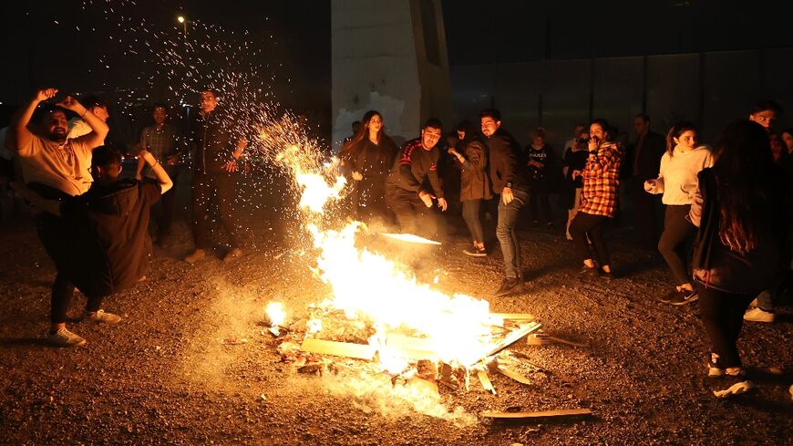 Iranians gather around a bonfire to mark the annual fire festival in the runup to Persian New Year, during which participants jump over the flames to ward off evil spirits
