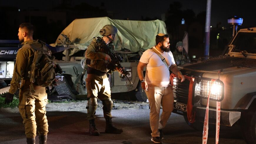 Israeli soldiers stand round a damaged military vehicle at the site of a car ramming attack near the town of Beit Ummar in the occupied West Bank