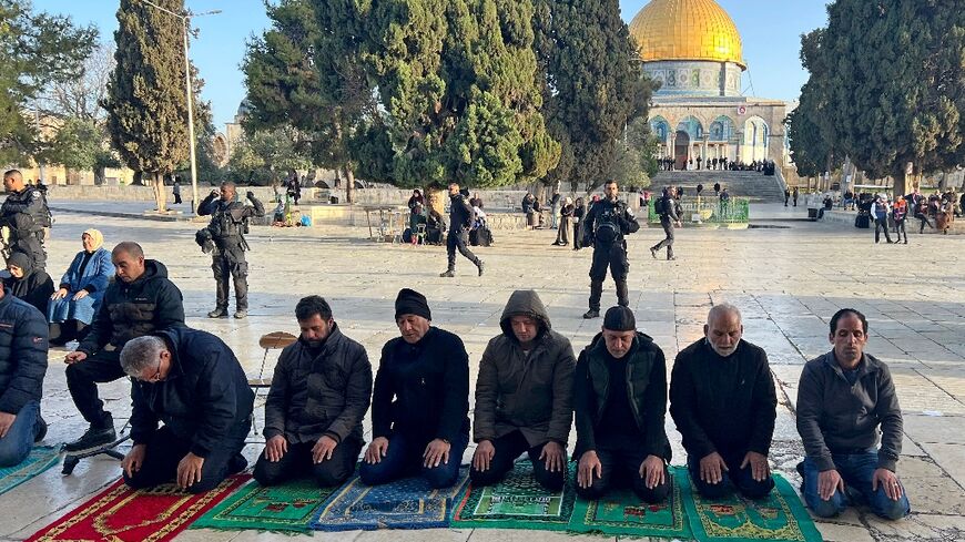 Israeli security forces stand guard as Palestinians pray in Jerusalem's al-Aqsa Mosque compound after officers earlier stormed the mosque's prayer hall 