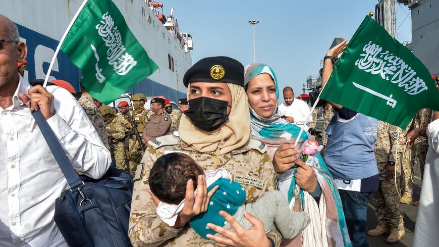 A Saudi Navy sailor carries a child as evacuees arrive at King Faisal Navy Base in Jeddah on April 26, 2023, following a rescue operation from Sudan 