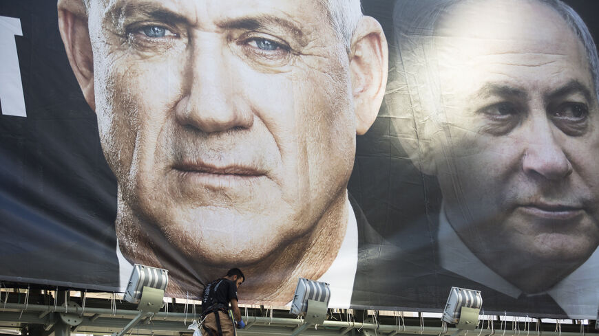 Workers hang a Blue and White Party billboard showing its leader Benny Gantz and Israeli Prime Minister, Benjamin Netanyahu.