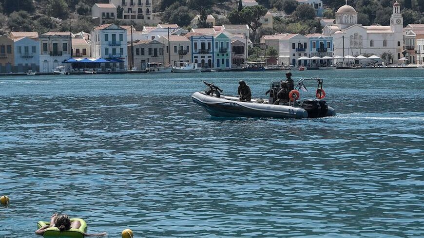 A woman enjoys the sea as a Greek army rib returns from patrol on the tiny Greek island of Kastellorizo.