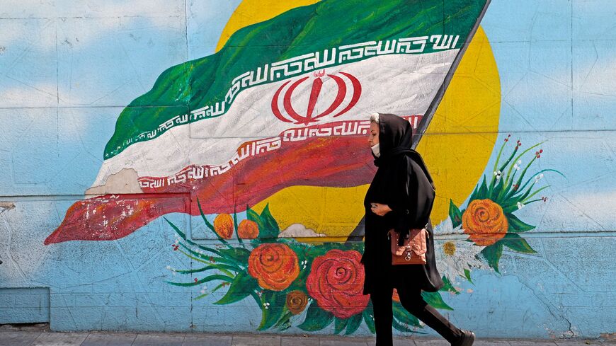 A woman walks past a mural in the Iranian capital Tehran, on October 11, 2022. (Photo by ATTA KENARE / AFP) (Photo by ATTA KENARE/AFP via Getty Images)
