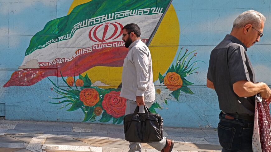 Men walk past a mural in the Iranian capital Tehran, on October 11, 2022. (Photo by ATTA KENARE / AFP) (Photo by ATTA KENARE/AFP via Getty Images)