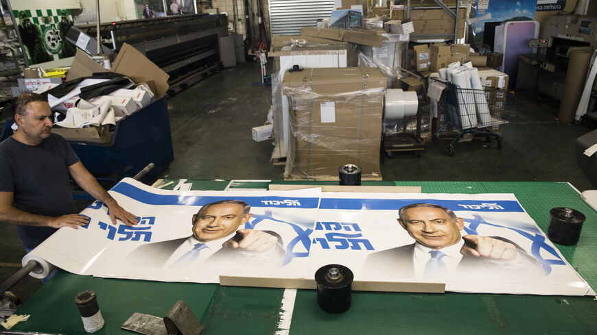 A print house worker rolls up a Likud party election campaign poster that shows former Israeli Prime Minister and Likud Party leader Benjamin Netanyahu on October 19, 2022 in Rosh HaAyin, Israel. Legislative elections will be held in Israel on 1 November 2022 to elect the members of the twenty-fifth Knesset. (Photo by Amir Levy/Getty Images)