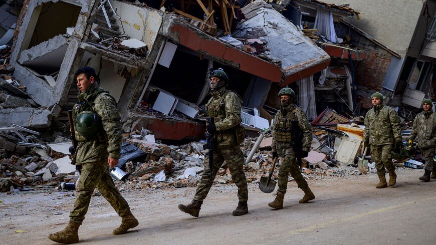 Turkish soldiers walk past a destroyed building in Hatay, on Feb. 11, 2023.