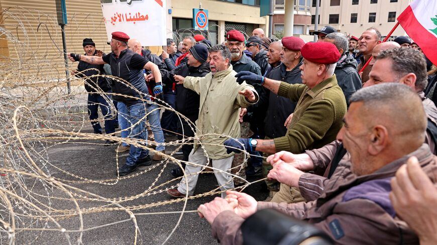 Retired Lebanese army and security forces veterans attempt to remove razor wire barricade during a demonstration demanding inflation-adjustments to their pensions, outside the government palace in Beirut on March 30, 2023. (Photo by JOSEPH EID / AFP) (Photo by JOSEPH EID/AFP via Getty Images)