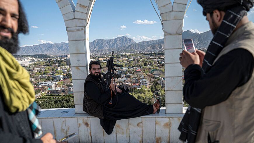 A Taliban security personnel take pictures of his colleague using a mobile phone at the Wazir Akbar Khan hilltop overlooking the Kabul city on April 4, 2023. 