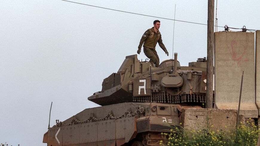 An Israeli soldier walks on the turret of a Merkava Mark IV battle tank stationed at a position along Israel's northern border with Lebanon in the vicinity of the village of Shtula on April 6, 2023. - The Israeli army said it intercepted rocket fire from Lebanon on April 6 after clashes between Israeli police and Palestinians inside Islam's third-holiest site drew warnings of retaliation from around the region. (Photo by Oren ZIV / AFP) (Photo by OREN ZIV/AFP via Getty Images)