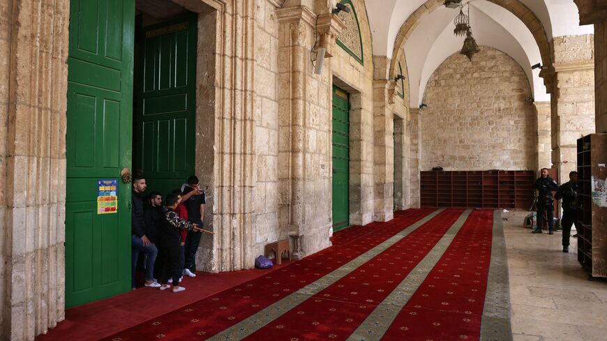 Palestinians stand inside the Al-Aqsa mosque as Israeli security forces watch at the Al-Aqsa mosque compound, also known as the Temple Mount complex to Jews, in Jerusalem on April 9, 2023, during the Muslim holy fasting month of Ramadan, also coinciding with the Jewish Passover holiday. (Photo by AHMAD GHARABLI / AFP) (Photo by AHMAD GHARABLI/AFP via Getty Images)