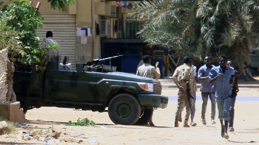 People run past a military vehicle amid clashes in the city, Khartoum, Sudan, April 15, 2023.
