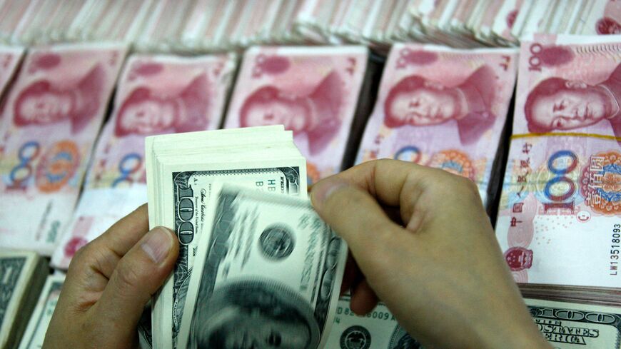 his picture taken on September 24, 2013 shows US dollar notes being counted next to stacks of Chinese 100 yuan (RMB) bank notes at a bank in Huaibei, in eastern China's Anhui province. With deals from London to Singapore, China is seeking to have its yuan currency used more widely around the world and challenge the hegemony of the almighty dollar. CHINA OUT AFP PHOTO (Photo by AFP) (Photo by STR/AFP via Getty Images)