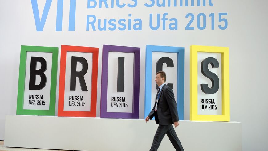 A man passes the BRICS summit logo at a hall in Ufa on July 9, 2015 prior to the start of the 7th BRICS summit. AFP PHOTO / ALEXANDER NEMENOV (Photo credit should read ALEXANDER NEMENOV/AFP via Getty Images)