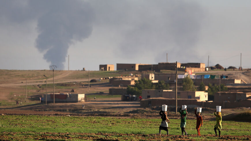Villagers walk to collect water after troops from the Syrian Democratic Forces, a coalition of Kurdish and Arab forces, retook a town on November 11, 2015 near Hasaka, in the autonomous region of Rojava, Syria. The armed forces of the predominantly Kurdish region in northern Syria have been retaking territory from ISIL extremists with the help of airstrikes from the U.S. led coalition. (Photo by John Moore/Getty Images)