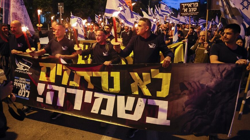 Opponents of the Israeli government's controversial judicial reform plans carry candles as they march through Tel Aviv ahead of the new session of parliament