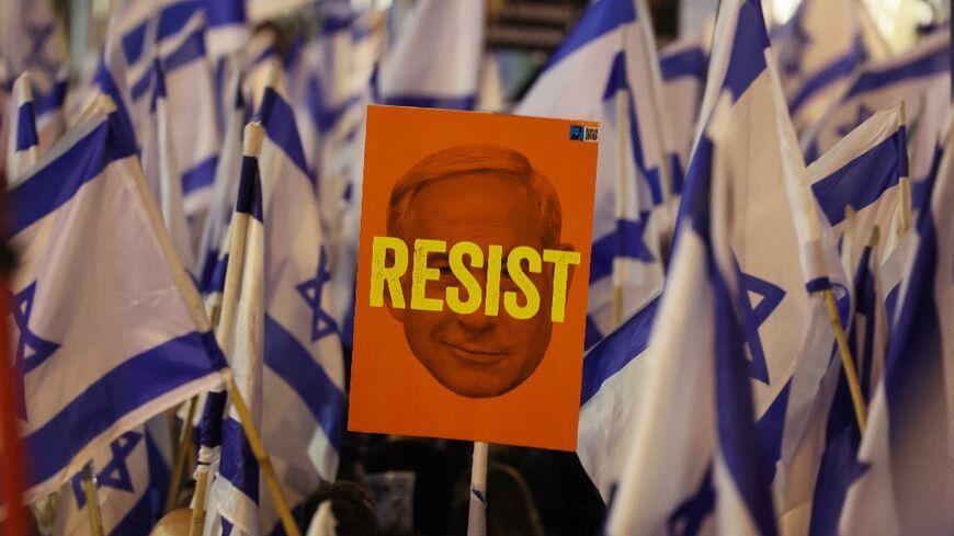 Demonstrators brandish Israeli flags and anti-Netanyahu placards  in Tel Aviv