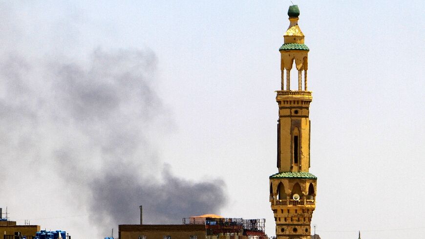 Smoke billows above buildings behind a mosque during fighting in Khartoum