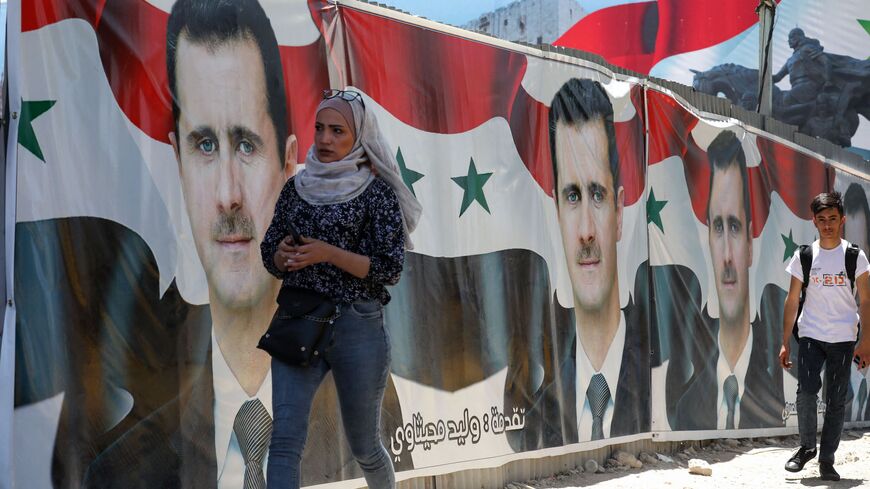 People walk past election campaign billboards depicting Syrian President Bashar al-Assad, a candidate for the upcoming presidential vote, in the capital Damascus, on May 25, 2021. 