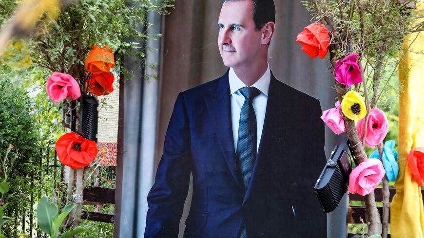 A large poster of Syrian President Bashar al-Assad is decorated with paper flowers during the opening of the 42nd International Flower Show in the Tishreen park in the capital Damascus on June 22, 2022. (Photo by LOUAI BESHARA / AFP) (Photo by LOUAI BESHARA/AFP via Getty Images)