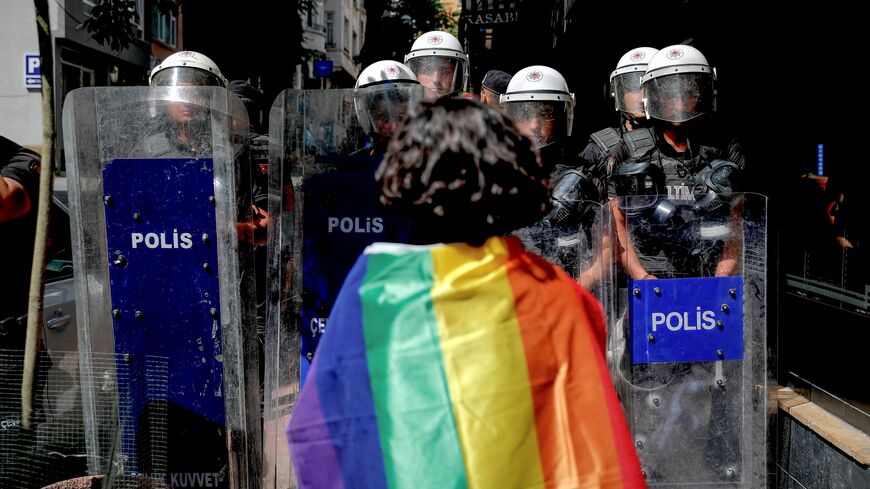 A participant faces riot policemen wearing a rainbow flag during a Pride march in Istanbul, on June 26, 2022. - Turkish police forcibly intervened in a Pride march in Istanbul, detaining dozens of demonstrators and an AFP photographer, AFP journalists on the ground said. The governor's office had banned the march around Taksim Square in the heart of Istanbul but protesters gathered nearby under heavy police presence earlier than scheduled. (Photo by KEMAL ASLAN / AFP) (Photo by KEMAL ASLAN/AFP via Getty Ima