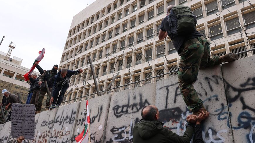Retired servicemen try to remove the barbed wire barricade outside Lebanon's central bank during a demonstration demanding inflation-adjustments to their pensions in Beirut on March 30, 2023. (Photo by JOSEPH EID / AFP) (Photo by JOSEPH EID/AFP via Getty Images)