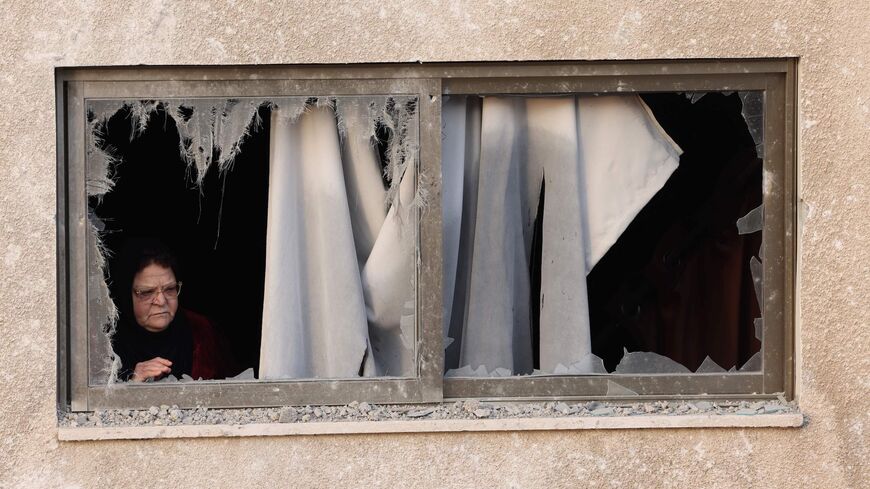 A woman looks out from the window of her damaged building after an Israeli airstrike in Gaza City, Palestinian territories.