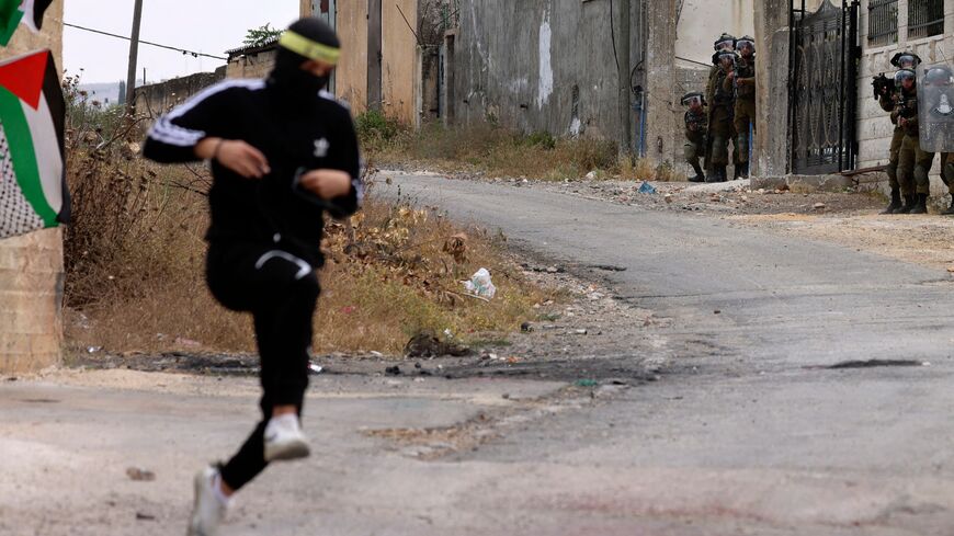 A Palestinian youth runs during confrontations with Israeli troops following a protest against the expropriation of Palestinian land by Israel in the occupied- West Bank, in the village of Kfar Qaddum, near the Jewish settlement of Kedumim, on May 19, 2023. (Photo by Jaafar ASHTIYEH / AFP) (Photo by JAAFAR ASHTIYEH/AFP via Getty Images)