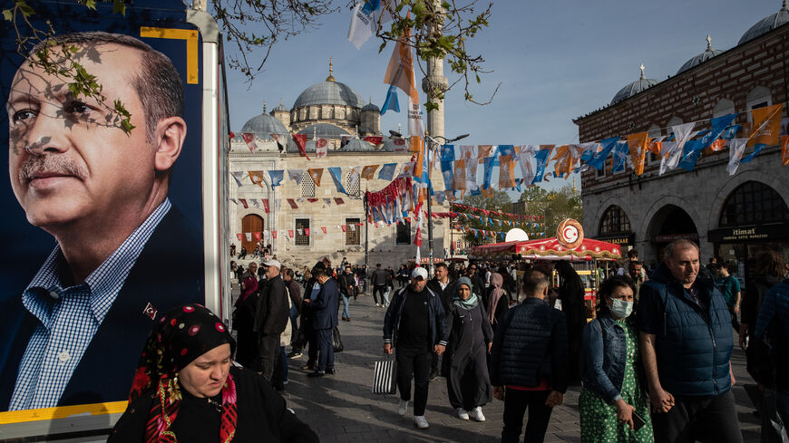 People walk past a campaign vehicle carrying a picture of Turkish President Tayyip Erdogan in a busy shopping district on May 03, 2023 in Istanbul, Turkey. Persistently high inflation has led to a cost-of-living crisis in Turkey that has hurt President Erdogan's popularity ahead of the March 14 presidential election. (Photo by Burak Kara/Getty Images)