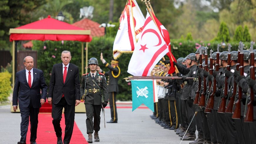 Turkish President Recep Tayyip Erdogan (R) walks alongside the leader of the self-proclaimed Turkish Republic of Northern Cyprus (TRNC), Ersin Tatar, during his post-election visit to Nicosia