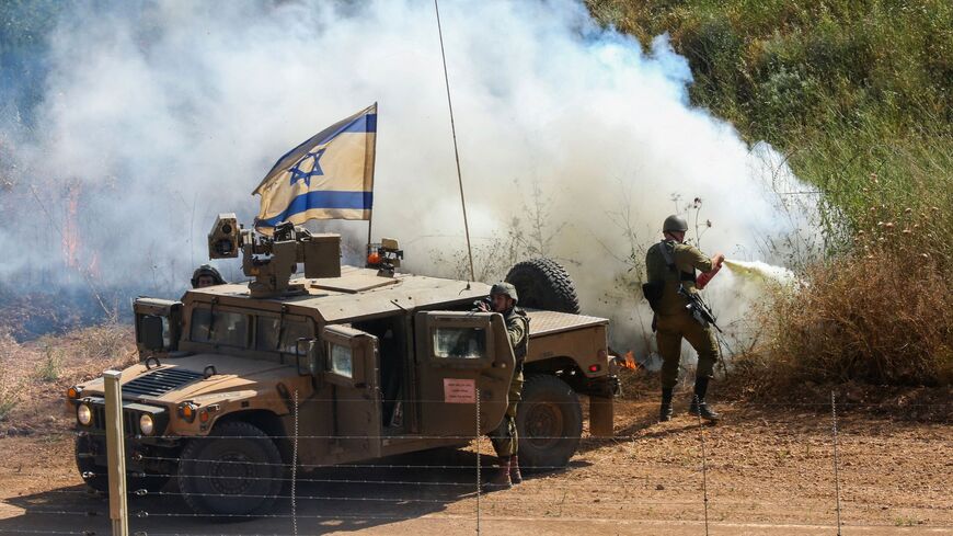 An Israeli soldier extinguishes a bush fire caused by a Molotov cocktail during clashes with pro-Hezbollah Lebanese demonstrators at the border near Marjayoun on May 25, 2023. (Photo by Mahmoud ZAYYAT / AFP) (Photo by MAHMOUD ZAYYAT/AFP via Getty Images)