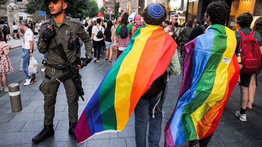 An Israeli border guard stands guard as people draped in rainbow flags march during the 21st annual Jerusalem Pride Parade in Jerusalem on June 1, 2023. (Photo by Menahem KAHANA / AFP) (Photo by MENAHEM KAHANA/AFP via Getty Images)