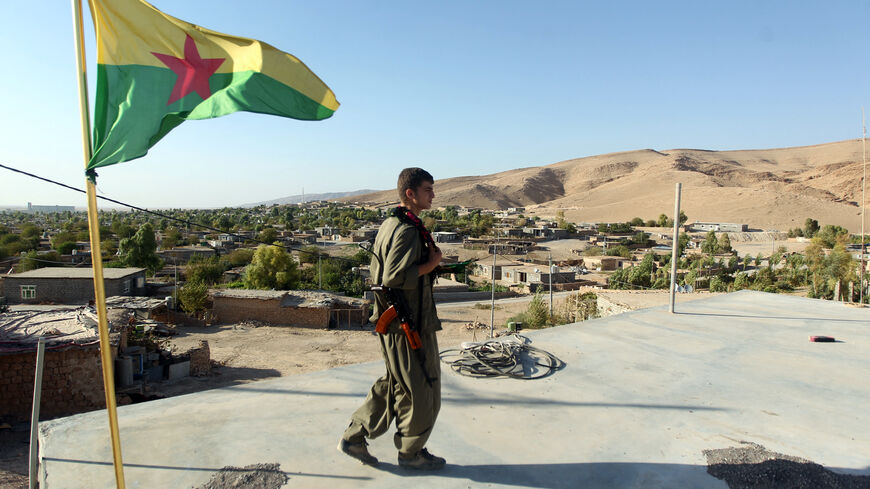 TO GO WITH AFP STORY BY SERENE ASSIR A Kurdistan Workers Party (PKK) fighters guards a post flying the PKK flag during the ongoing intensive security deployment against Islamic State (IS) militants in the town of Makhmur, southwest Arbil, the capital of the autonomous Kurdish region of northern Iraq, on August 21, 2014. Kurdish groups from Iraq and three neighbouring countries are putting aside old rivalries to battle jihadist militants, but there are cracks in this newly-forged unity and it may not last. A