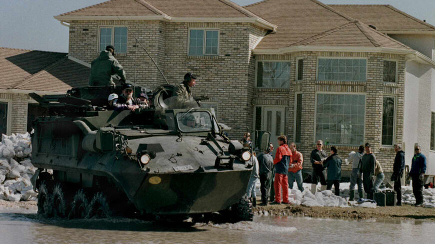 The Canadian Military in an armoured personel carrier drive away from a house that is flooding after dropping off people to sandbag because of high water levels on the Red River in Winnipeg, Manitoba 30 April. The water on the Red River continues to rise and over 20,000 people have been evacuated from their homes. AFP PHOTO/Carlo ALLEGRI (Photo credit should read CARLO ALLEGRI/AFP via Getty Images)