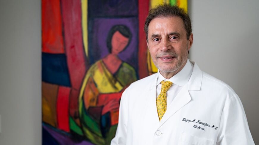 Hagop Kantarjian, M.D., poses with one of his favorite paintings, "Seated Woman with Red Guitar" (2021).
