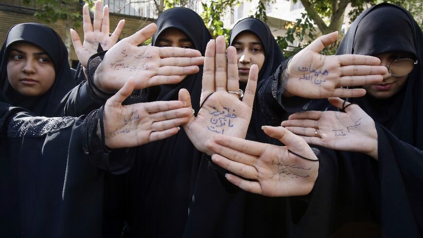 Demonstrators outside Sweden's Tehran embassy show slogans on their hands as they  denounce the Stockholm protest