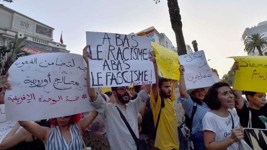 Demonstrators lift placards and chant anti-racism slogans during a protest in Tunis in support of migrants
