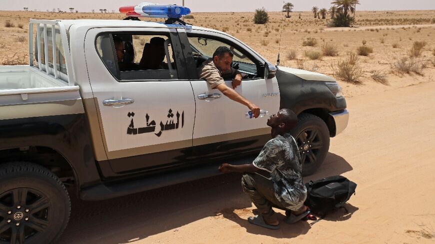 A Libyan border guard gives water to a migrant during a rescue operation in an uninhabited area near the town of Al-Assah on the border with Tunisia 