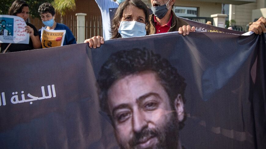 The mother of imprisoned journalist Omar Radi holds up a banner with his photo in a protest in Casablanca on September 22, 2020